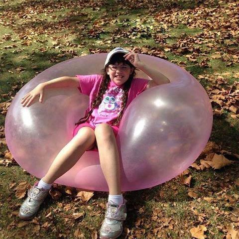 Girl sitting on air wubble bubble ball in garden